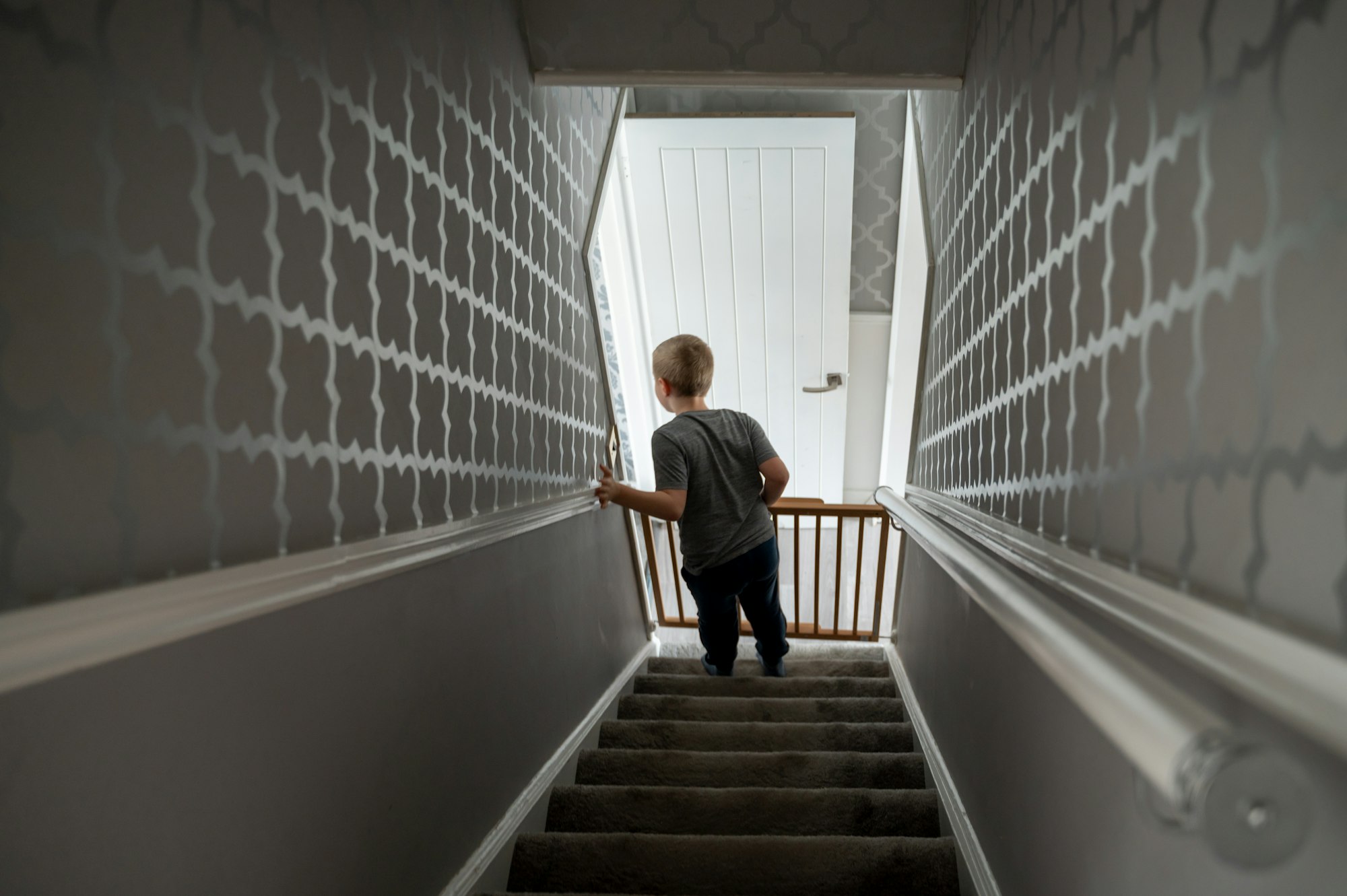 Child going down the stairs at home with baby safety gate