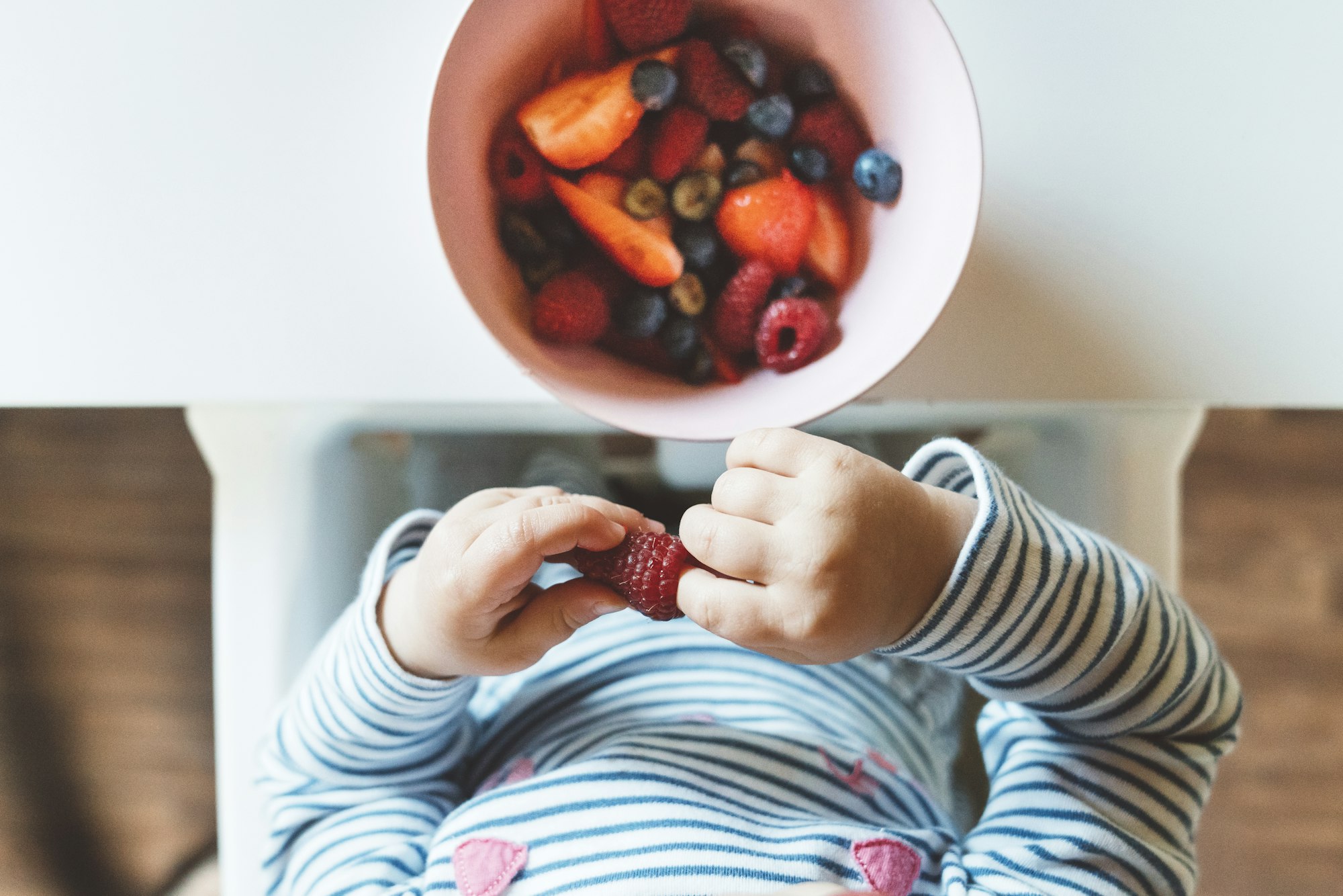 The baby is trying a new taste of solid food. Eating healthy food from the beginning is important. Y