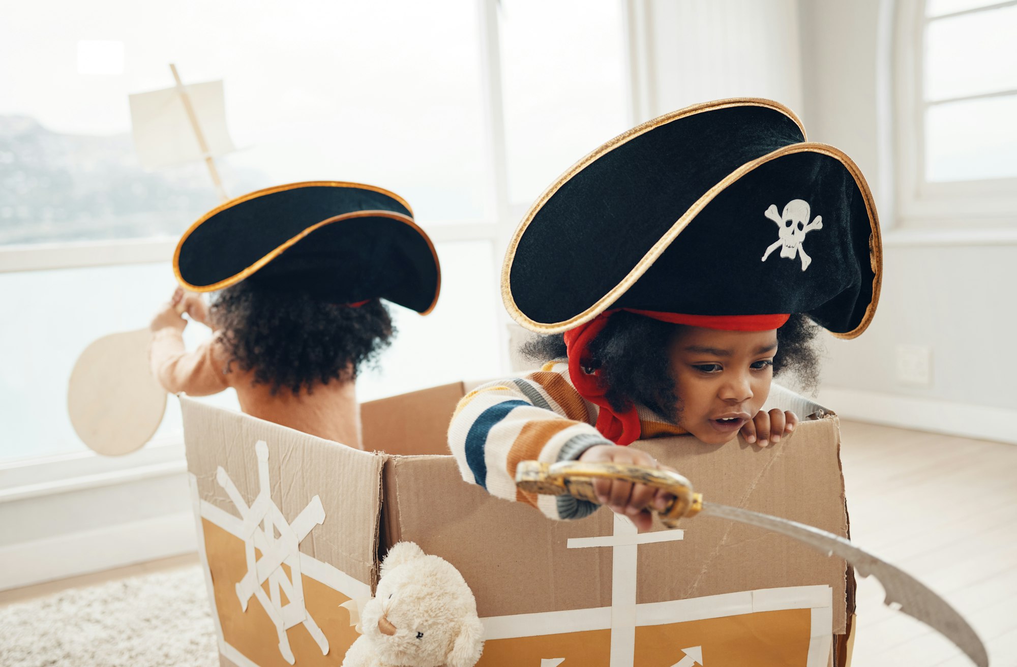 Playing, box ship and pirate children role play, fantasy imagine or pretend in cardboard container.