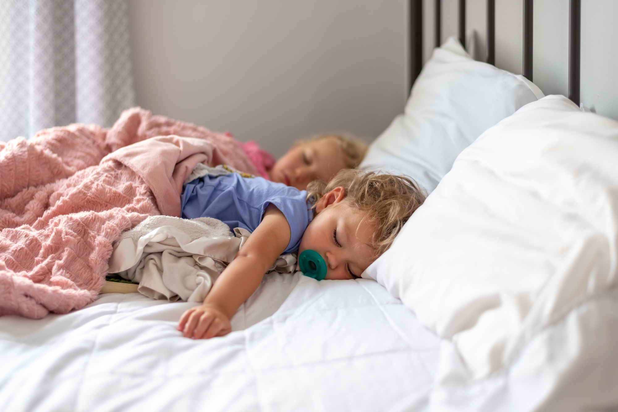 Two little girls napping on a big white bed