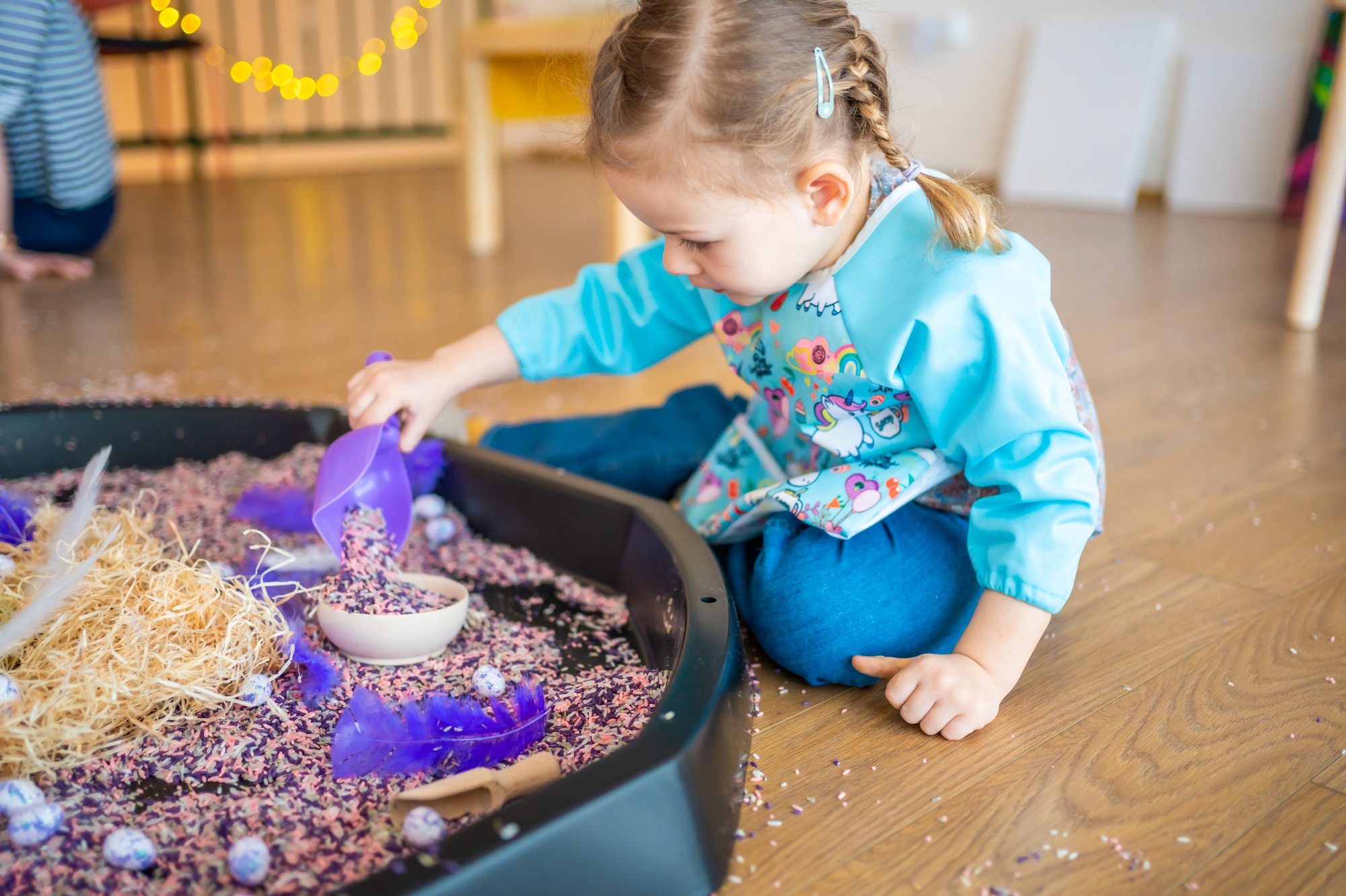 Little girl playing with sensory colorful rice. Sensory development and experiences, themed