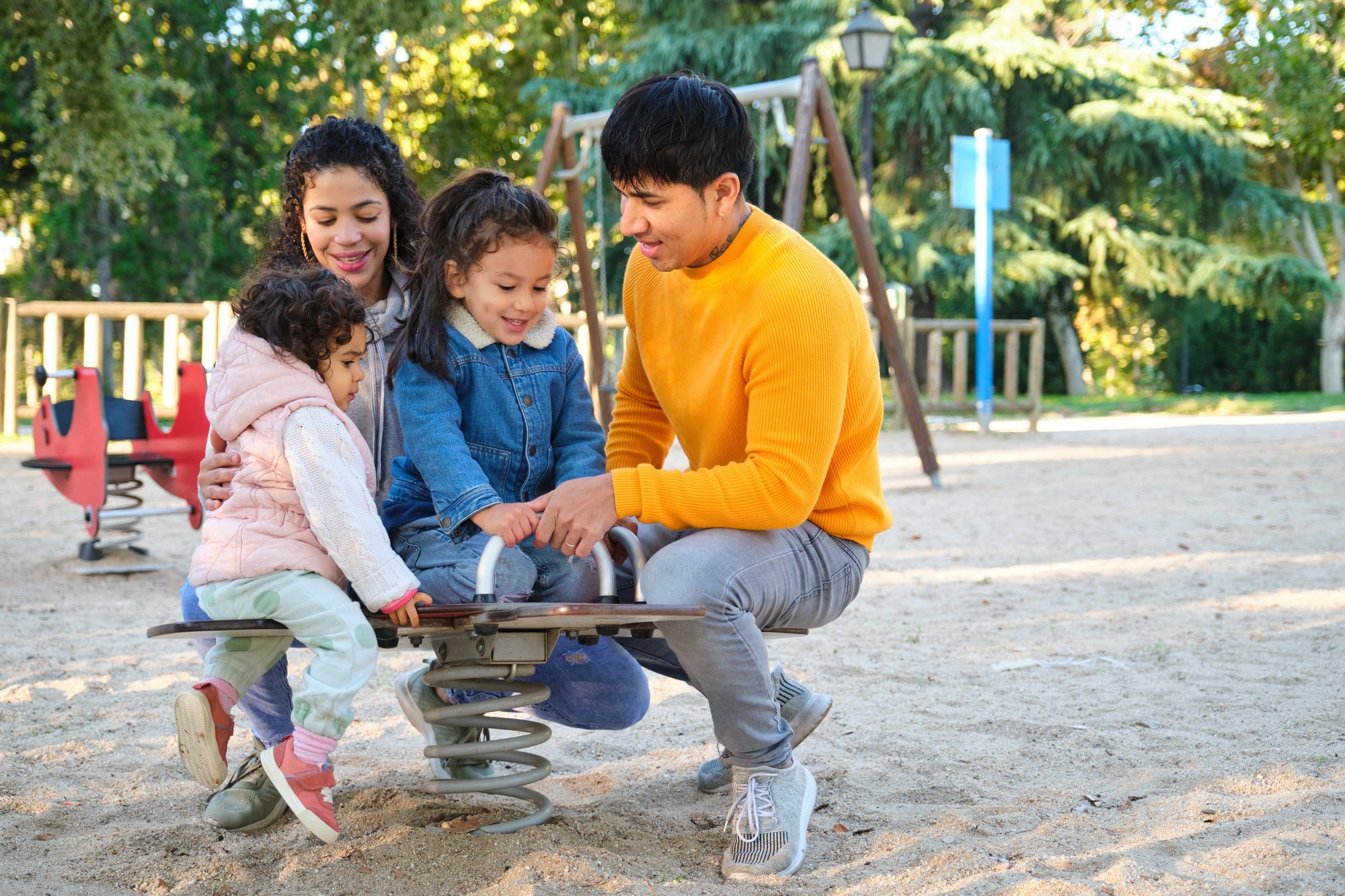 Hispanic family with two children playing together in a playground.