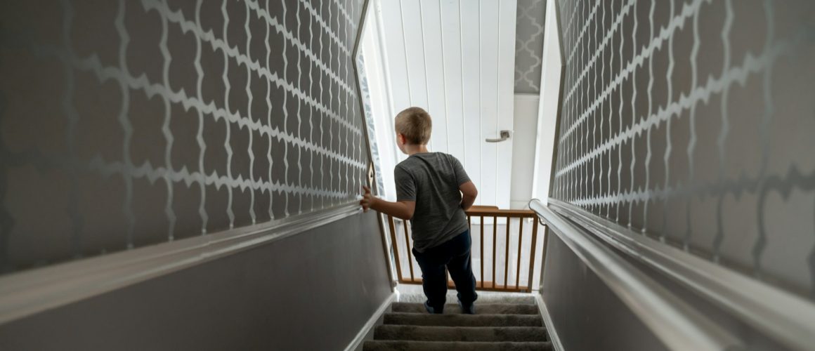 Child going down the stairs at home with baby safety gate