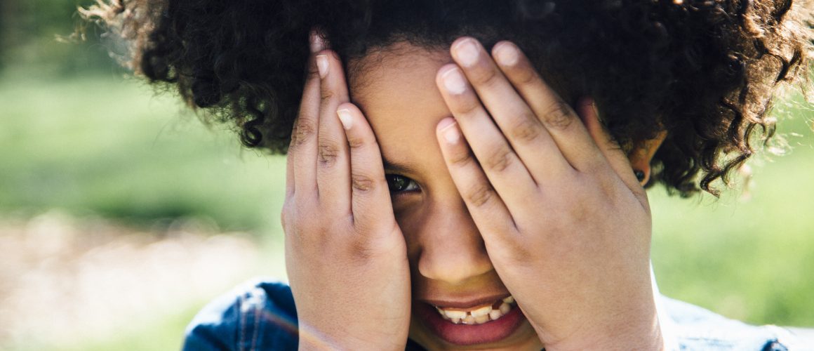 Close up portrait of girl covering face with hands