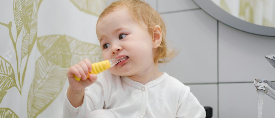 Kids personal hygiene. A toddler brushing teeth in bathroom. Teaching children morning routine.